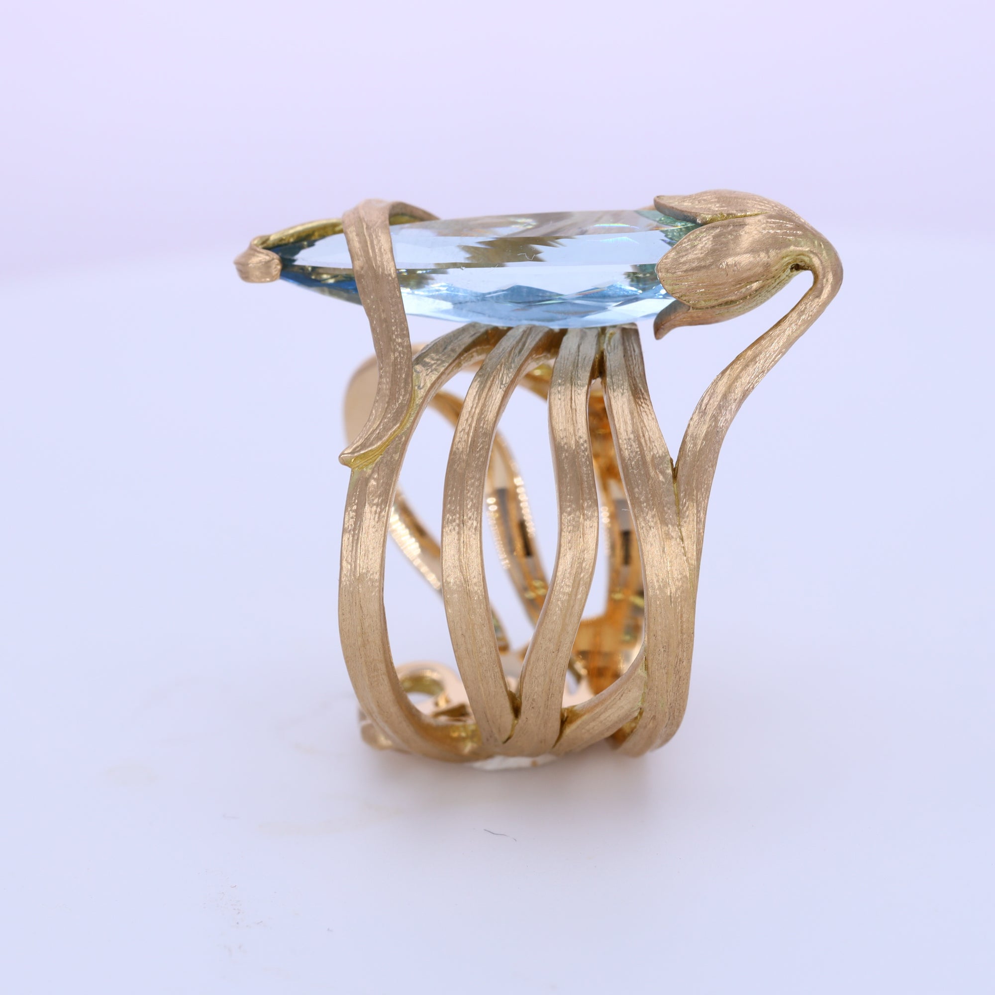 Art Nouveau aquamarine and 18K gold ring designed as scrolling leaves wrapped around the ring finger and gold sepals securing the aquamarine